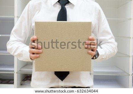 Young businessman holding brown box, closeup