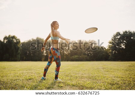 Young athletic girl playing with flying disc in the park. Professional player. Sport concept. Focus on flying disc