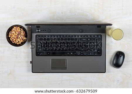 Business lap top flat lay with peanuts and juice.