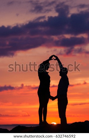 Silhouettes of woman and man on a background of colorful sunset of a cloudy day on the beach