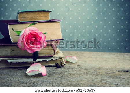 Old books with flower pink rose on the old board.