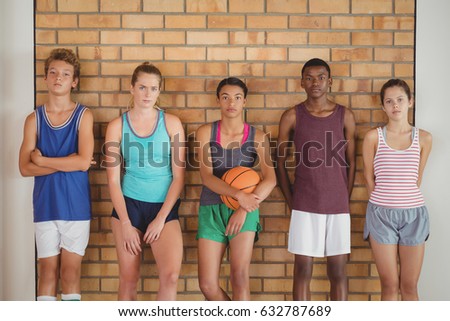 Portrait of high school kids leaning against the wall in basketball court