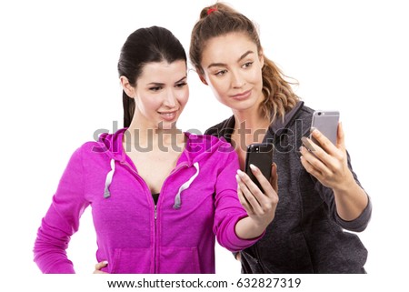 young casual caucasian women wearing sport outfits on white isolated background. Holding mobile phones.