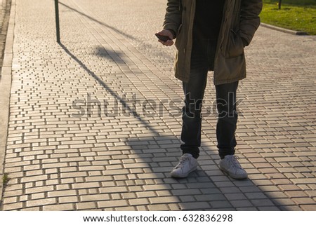 Portrait of handsome young man using his mobile phone in the street in sanly day