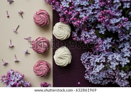Pink and white marshmallows on a table with lilac flowers. Sweets and food in the kitchen.