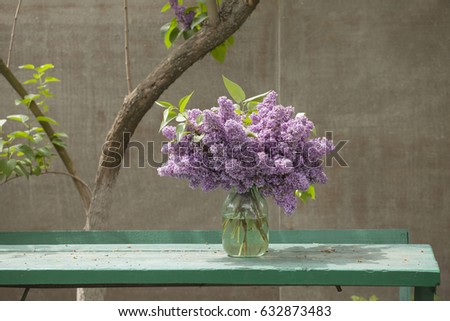A bouquet of lilacs on a wooden table in the garden