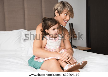 Curious mother and daughter watching tv in bedroom