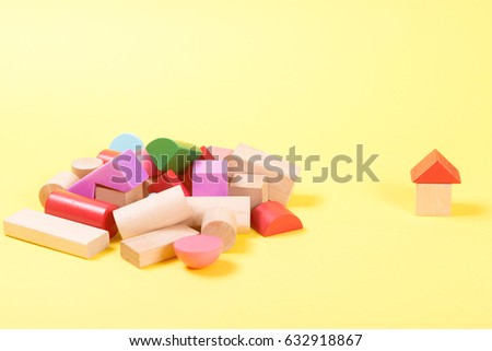 Colorful wooden building blocks on the yellow background.