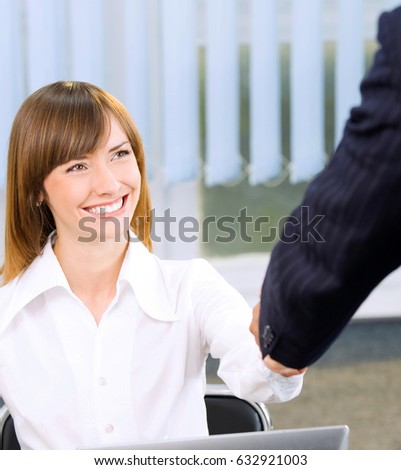 Two happy smiling businesspeople, or businesswoman and client, handshaking at office. Success in business and teamwork concept.