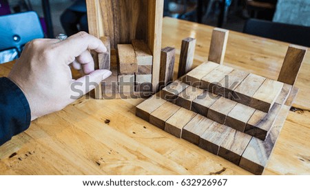The tower from wooden blocks and man's hand take one block