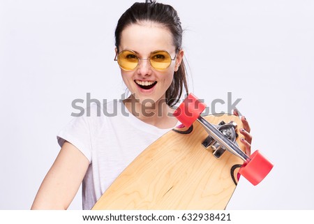 A girl with a skateboard in her hands  in glasses surprised                               