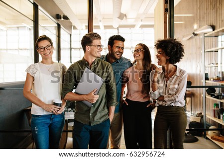 Portrait of successful business team standing together and smiling. Multi ethnic business people at startup. Royalty-Free Stock Photo #632956724