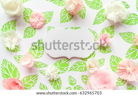 round frame with color paper flowers on the white background of green leaves. cut from white paper. Place your text