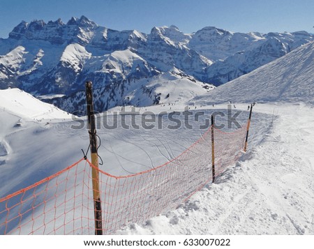 Snow fence lines the piste  on a steep descent in the Portes du Soleil, Switzerland
