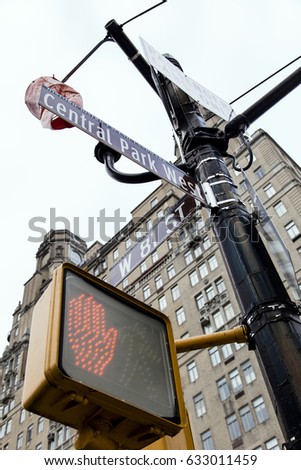 Low angle view of street signs depicting it is the intersection between Central Park West and West 81 st. in Manhattan, New-York, with red pedestrian traffic light.