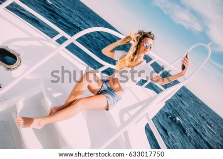 Young girl sitting on the yacht and taking selfie with sea