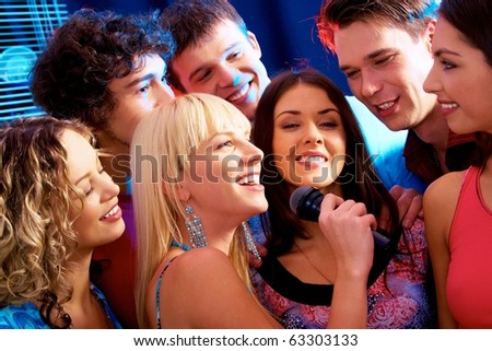 Image of happy young woman sings a song in the environment of her friends