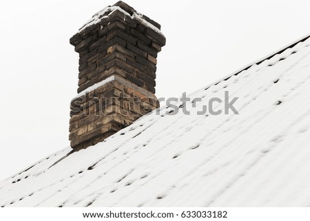  photograph of the roof of a house made of slate covered with snow falling during a snowfall