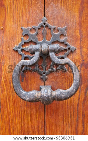 Old metal door handle knocker on wooden background