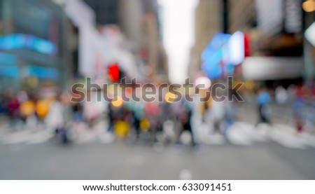 Busy New York City street with people walking, taxis driving and pedestrians crossing the street. Blurred urban background with neutral tones and creative focus.