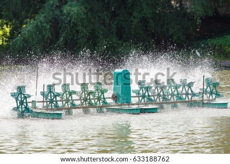 Aerator paddle wheels filling oxygen in pond or lake, water treatment concept, high speed shutter