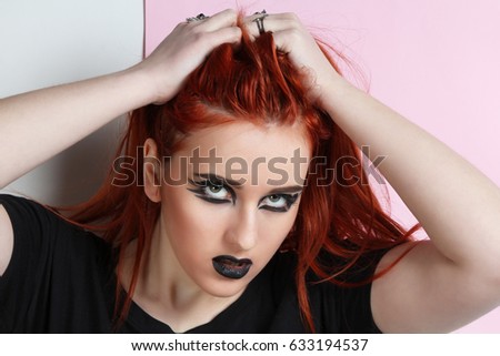 Red-haired girl with black make-up on a pink background