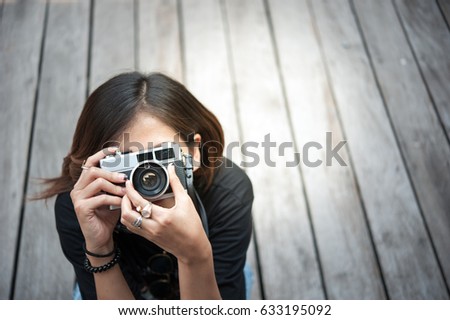 Hipster woman taking photos with retro film camera  on wooden floorof city park,beautiful girl photographed in the old camera
