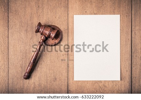 Auction or judge gavel and textured paper blank on wooden table background. Retro style filtered photo