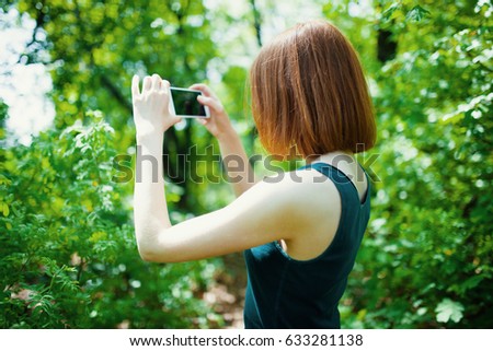 young woman make photo on cellphone, spring flowers background