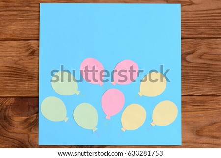 Making a card with paper air balloons. Step. Lesson for children. Card with paper air balloons isolated on a wooden table. Preschool and kindergarten crafts activities. Closeup. Top view