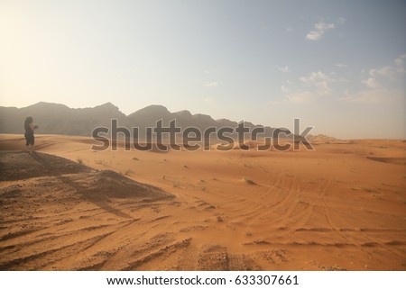a lady photographer in mountain area, desert and sky background
