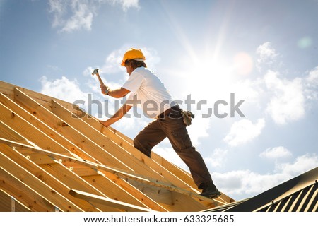 roofer working on roof structure of building on construction site Royalty-Free Stock Photo #633325685