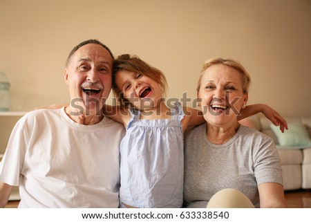 Grandmother and grandfather playing end enjoying with their granddaughter.  Royalty-Free Stock Photo #633338540