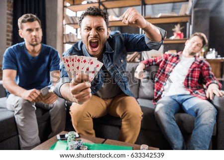 Triumphing young man sitting on sofa and showing street flash of diamonds combination
