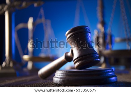 Paragraph symbol, book and judge's gavel on wooden table. Variety of scales of justice in bokeh on blue background. Law concept background