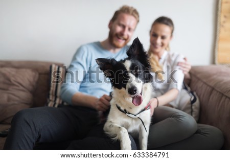Beautiful couple relaxing at home and loving their pet Royalty-Free Stock Photo #633384791