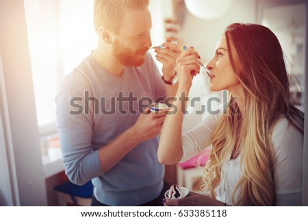 Beautiful couple having fun and laughing at home while eating ice cream Royalty-Free Stock Photo #633385118