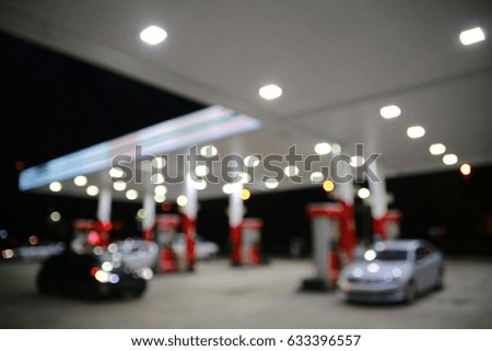 Abstract, Impressionistic Wallpaper Background of Gas Station at Night with Cars at Pump and Car Driving By Out of Focus