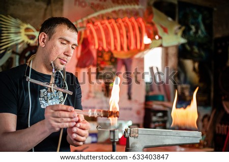 Glass-blowing workshop. Burner. Production of neon tubes. Worker using the heat of gas blowing glass to look as art, shape, light, flame beautiful.