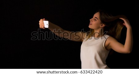 Pretty girl makes selfie Black background