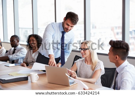 Businessman Stands To Address Meeting Around Board Table