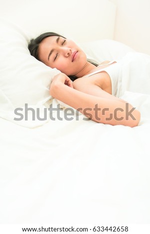 Beautiful young asian woman with attractive smile laying on bed indoors Portrait of woman in bedroom