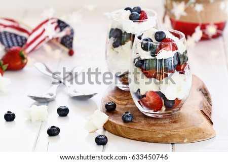 Trifle made with blueberries, strawberries, whipped cream and star shaped pound cake sitting on a Fourth of July picnic table. Shallow depth of field with selective focus.