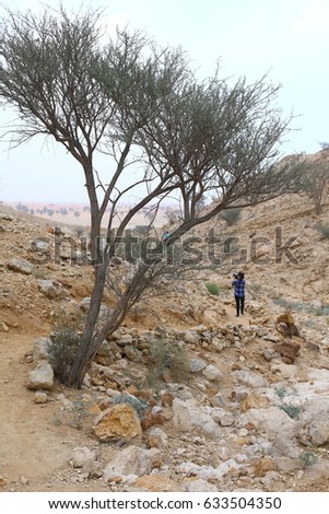 a lady photographer standing in mountain area, desert cloud, rock and sky background. United Arab Emirates.