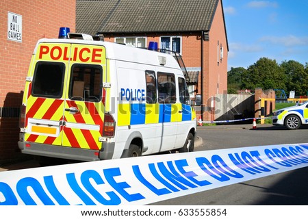 British Police vehicles at cordoned off crime scene in a typical English town