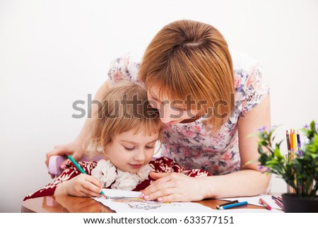 Young mom and her little daughter drawing together with colorful pencils