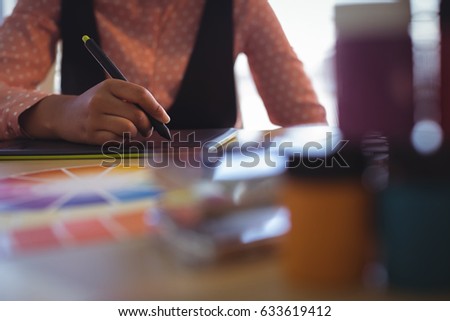 Mid section of businesswoman working on digitizer at creative office desk