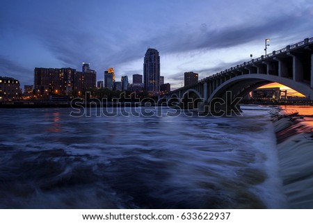 The St Anthony Falls on the Mississippi River Flow in front of Downtown Minneapolis and the 3rd Ave Bridge as Night Falls
