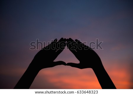 Silhouette of asian woman make hand shape heart on head on sunset