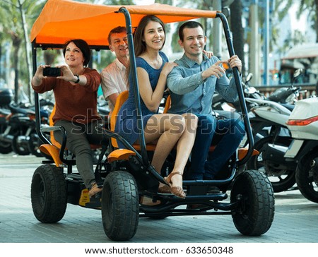 Positive four people traveling through city by grand tour electric